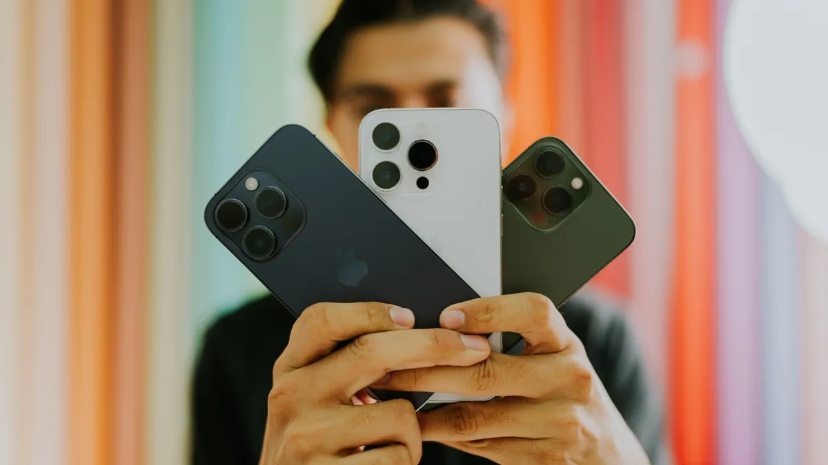 person holding three different smartphones